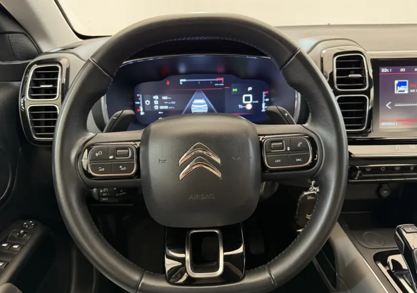 Vue rapprochée du volant cuir noir de la Citroën C5 Aircross 2020 avec tableau de bord numérique et écran tactile.