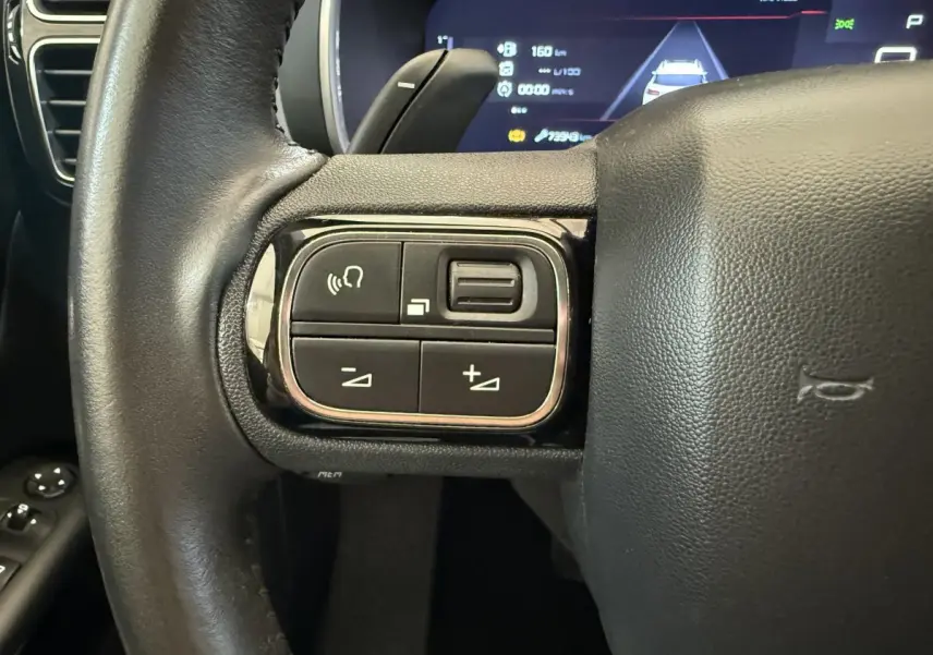 Gros plan sur les commandes gauche du volant cuir noir du Citroën C5 Aircross 2020 avec affichage numérique en arrière-plan.