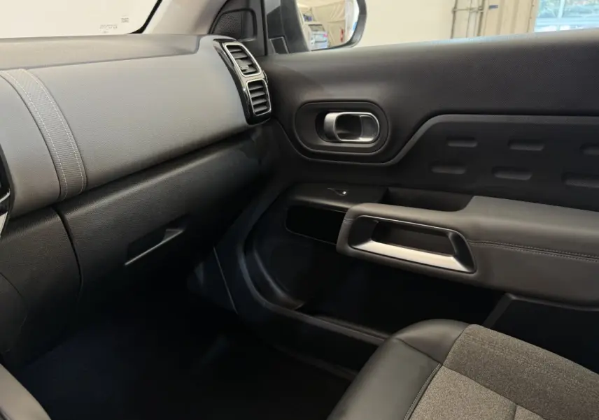 Intérieur côté passager du Citroën C5 Aircross gris clair, montrant tableau de bord et porte avec détails en tissu et cuir noir.