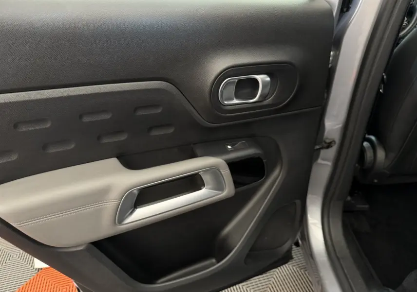 Vue intérieure côté gauche de la porte arrière grise du Citroën C5 Aircross avec poignée argentée et garniture noire et grise.