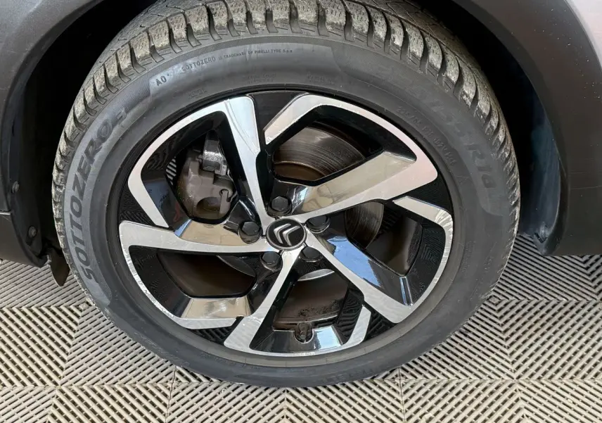 Gros plan sur la roue avant droite du Citroën C5 Aircross gris clair, avec jante alliage bicolore et logo Citroën central.