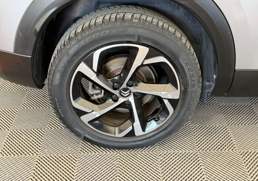 Gros plan sur la roue avant gauche gris clair du Citroën C5 Aircross avec jante alliage noire et argentée au design moderne.