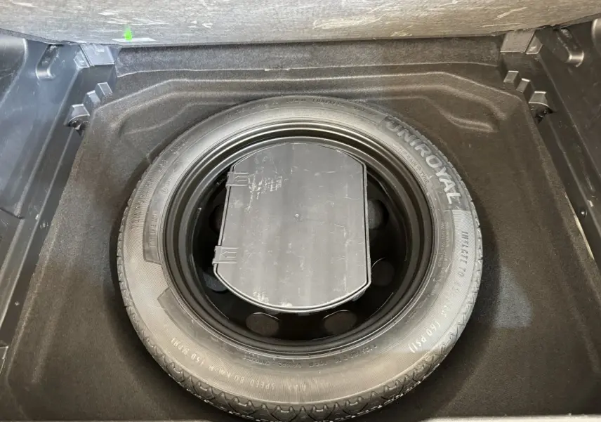 Vue plongeante sur la roue de secours Uniroyal dans le coffre d'un Citroën C5 Aircross gris clair 2020.
