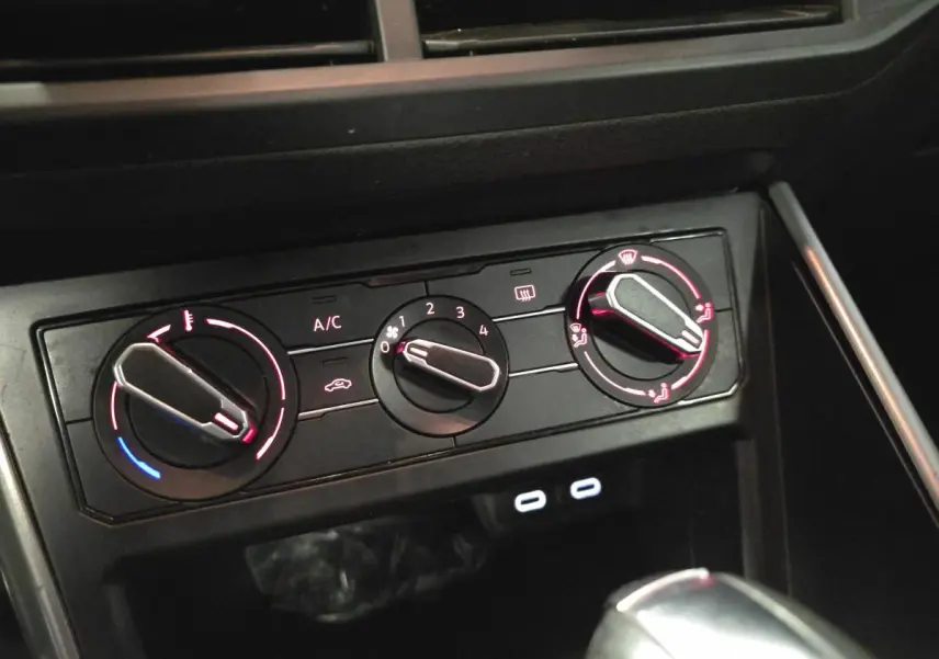 Gros plan sur la console centrale de la Volkswagen Polo 2020 avec commandes de climatisation manuelle et ports USB-C éclairés.