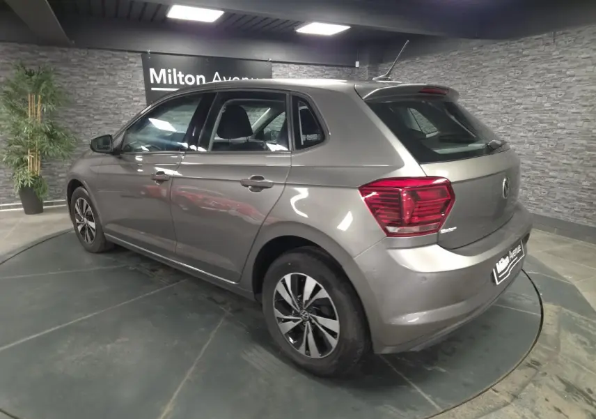 Vue 3/4 arrière droite d'une Volkswagen Polo gris métallisé avec jantes alliage et feux arrière rouges.