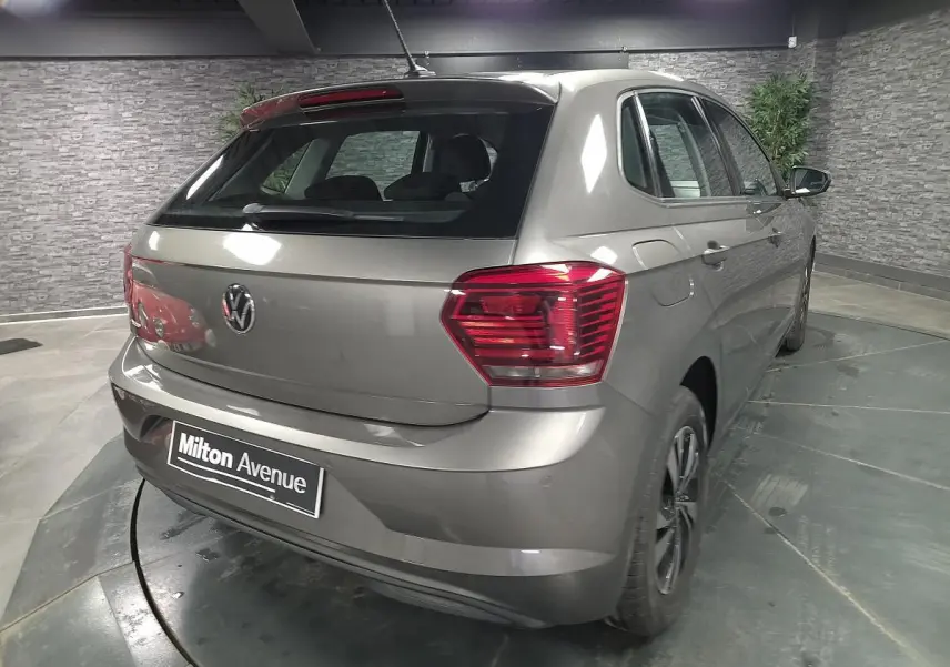 Vue 3/4 arrière droite d'une Volkswagen Polo gris métallisé avec jantes alliage et antenne de toit.