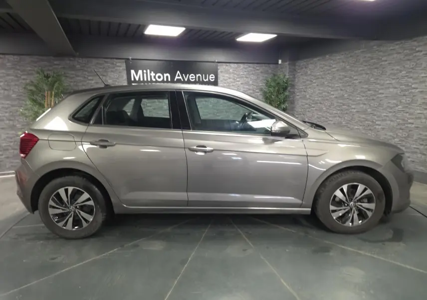 Profil droit d'une Volkswagen Polo gris métallisé 2020 avec jantes alliage 15 pouces en intérieur showroom.