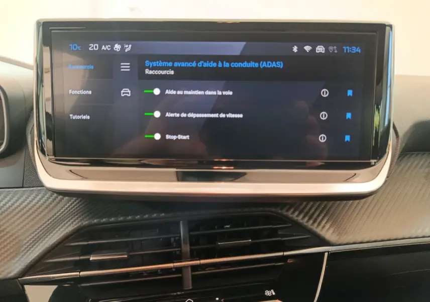 Écran tactile central affichant les aides à la conduite dans l'habitacle noir de la Peugeot 208 PureTech 100 S&S Allure.