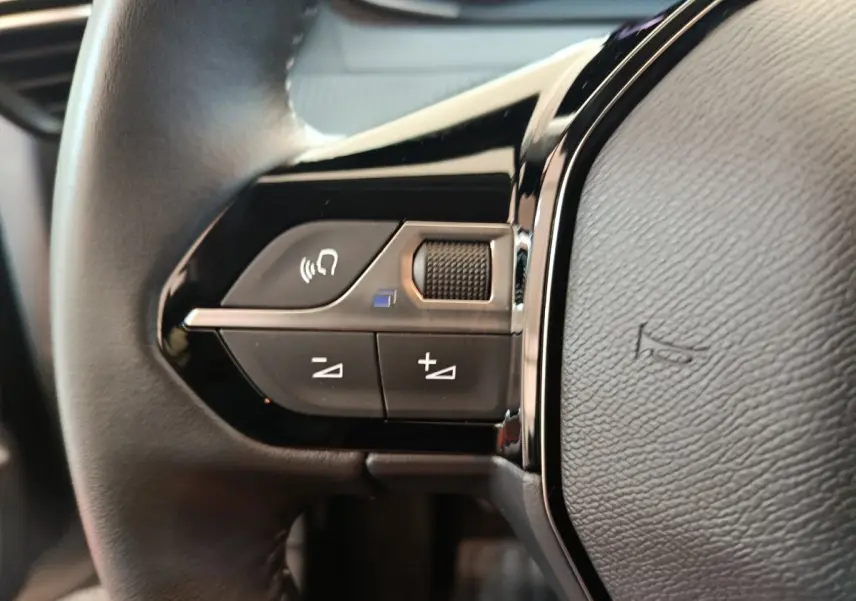 Gros plan sur les commandes audio et vocales du volant cuir côté gauche de la Peugeot 208 gris foncé 2025.