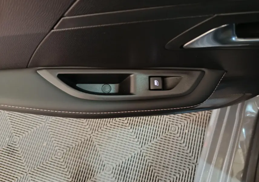 Poignée intérieure côté gauche de porte en cuir noir avec bouton de verrouillage sur Peugeot 208 gris foncé 2025.