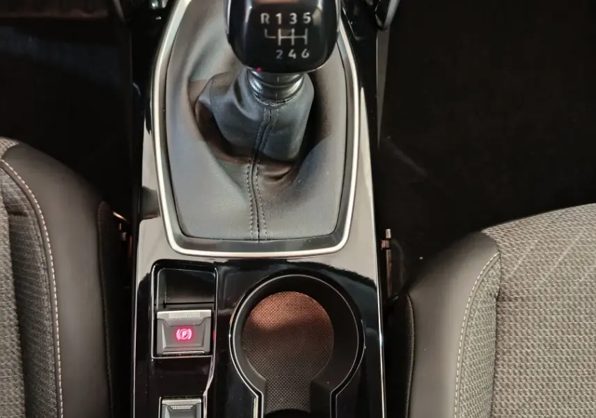 Vue plongeante sur la console centrale noire de la Peugeot 208 PureTech 100 S&S Allure avec levier de vitesse manuel et porte-gobelets.