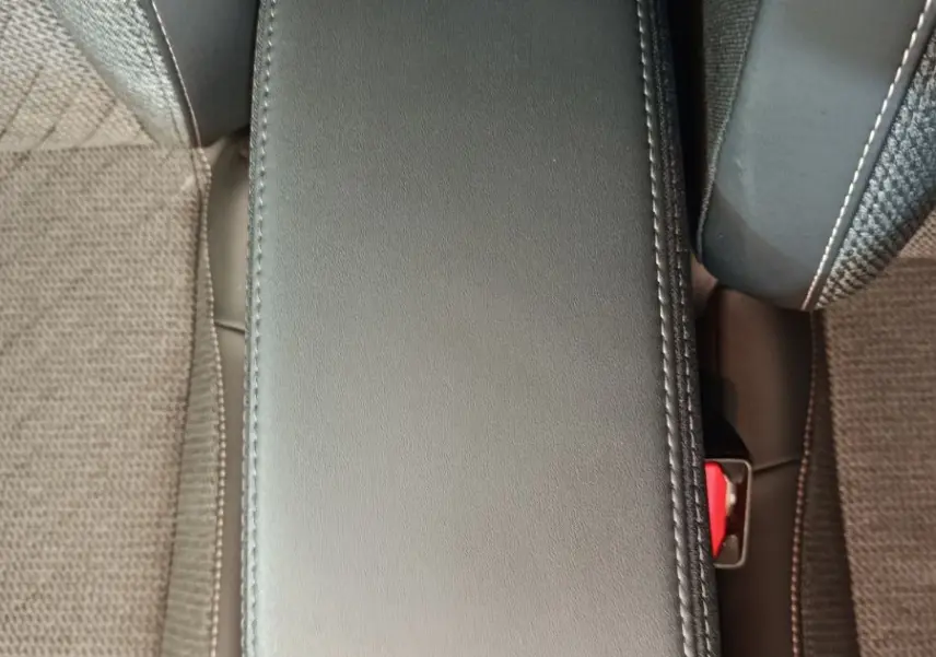 Accoudoir central avant en cuir gris foncé entre les sièges tissu de la Peugeot 208 PureTech 100 S&S Allure 2025.