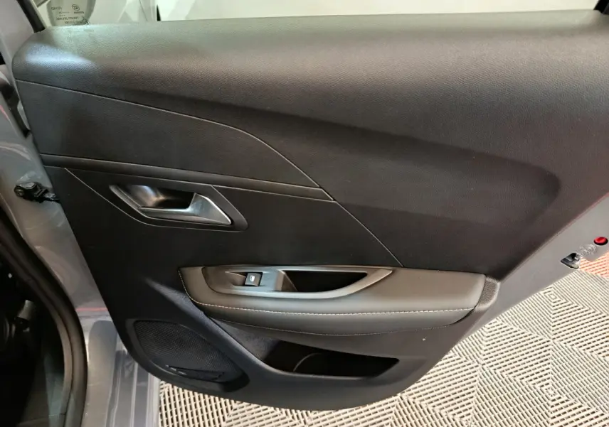 Vue intérieure de la porte côté gauche grise de la Peugeot 208 PureTech 100 S&S Allure avec poignée et commande de vitre.