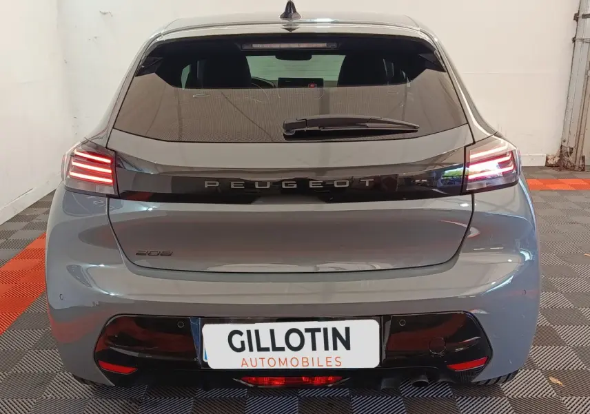 Vue arrière d'une Peugeot 208 gris foncé avec feux LED allumés et logo Peugeot visible sur le hayon.