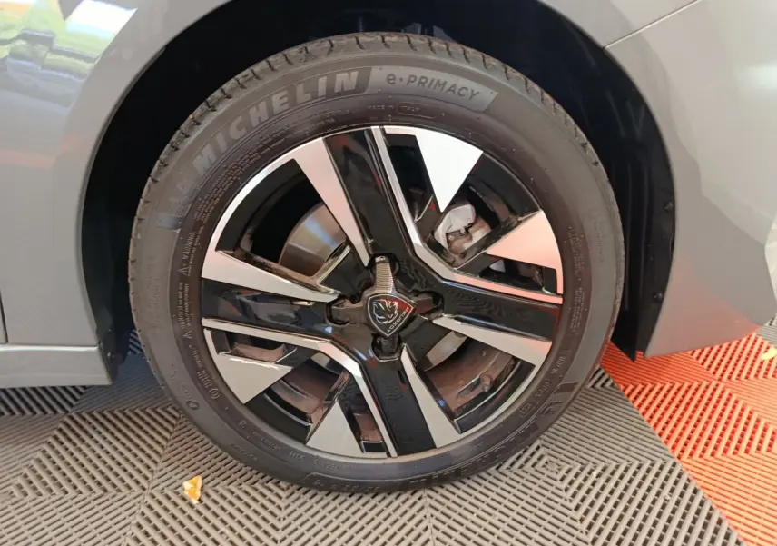 Gros plan sur la roue avant droite de la Peugeot 208 gris foncé avec jante alliage noire et argentée au design moderne.