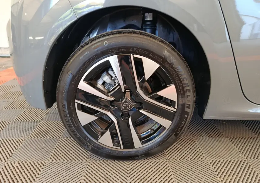 Gros plan sur la roue avant gauche grise d'une Peugeot 208 PureTech 100 S&S Allure avec jante alliage bicolore.