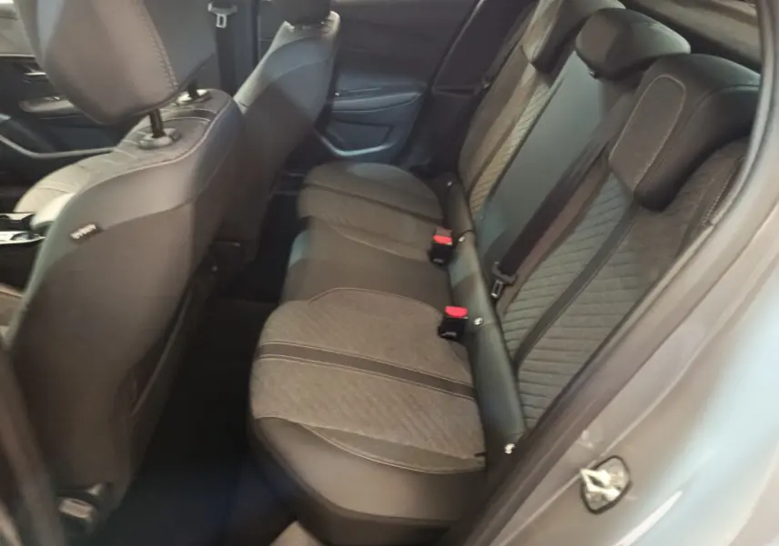 Vue côté droit de l'intérieur arrière de la Peugeot 208 gris foncé avec sièges tissu et cuir bicolores.