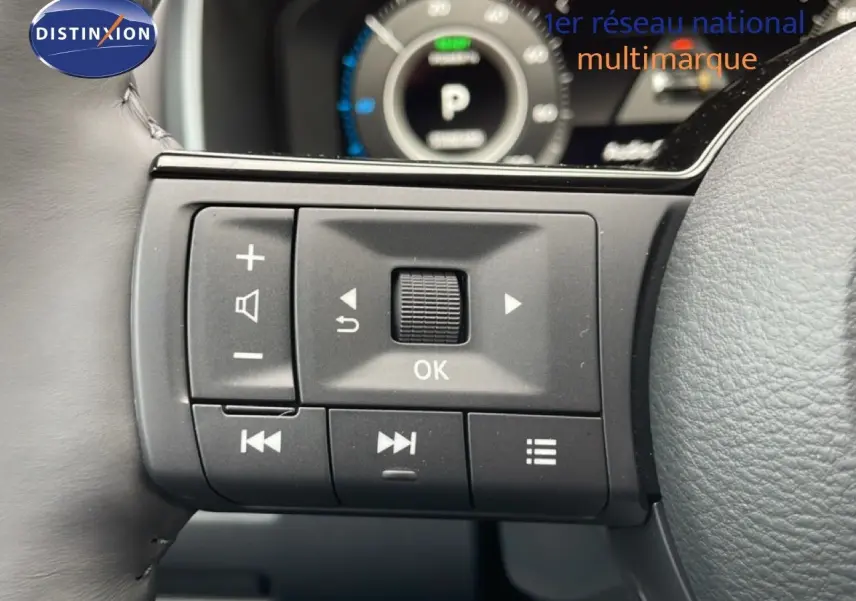 Gros plan sur les commandes au volant du Nissan Qashqai gris squale métal, avec affichage numérique en arrière-plan.