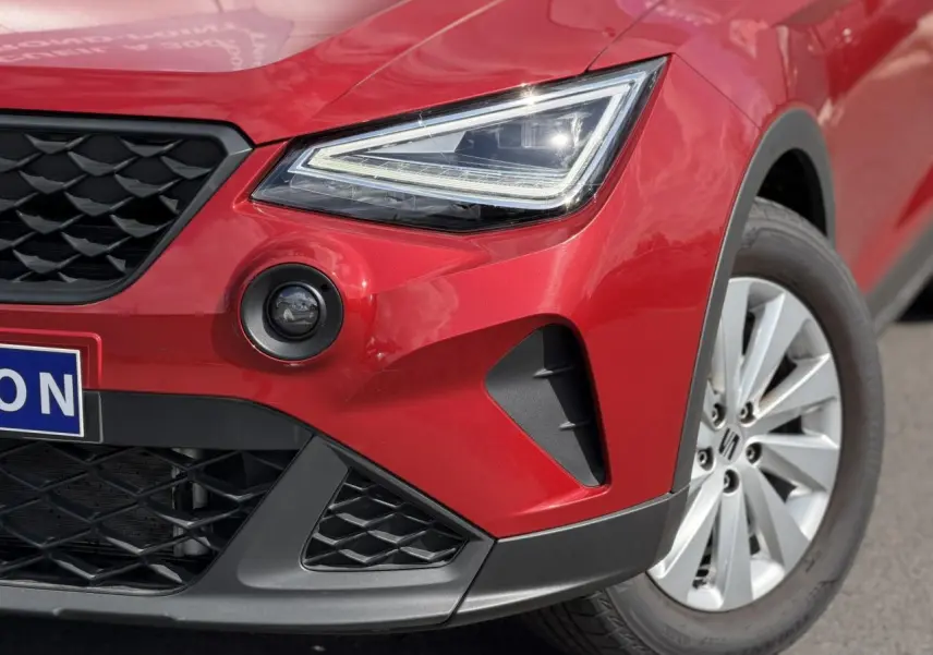 Gros plan sur l'avant droit du SEAT Arona Rouge Désir, mettant en valeur le phare LED et la jante alliage 16 pouces.