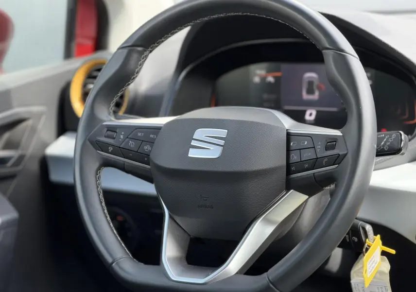 Vue rapprochée du volant multifonctions noir de la SEAT Arona 2025 avec tableau de bord digital en arrière-plan.