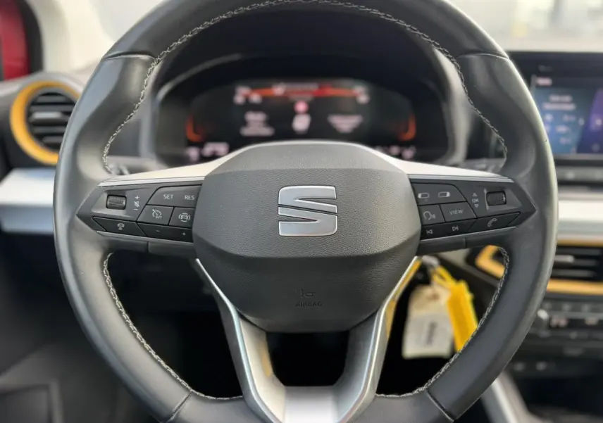 Vue rapprochée du volant noir de la SEAT Arona 2025 avec commandes intégrées et détails jaunes sur la planche de bord.