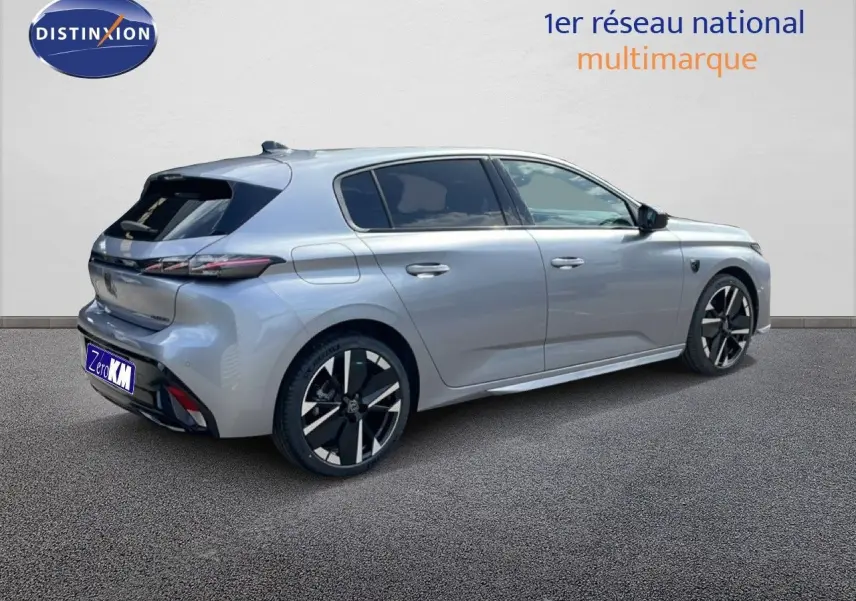 Peugeot 308 1.2 Hybrid gris Artense métal vue 3/4 arrière droit avec jantes noires et détails modernes.