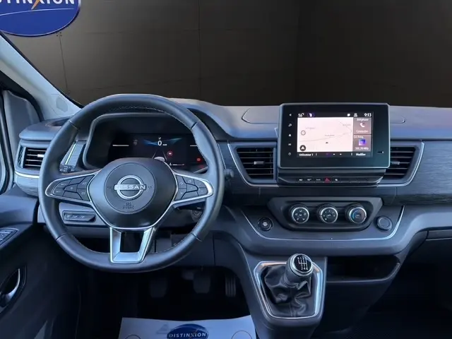 Vue intérieure frontale du tableau de bord et volant cuir synthétique du Nissan Primastar gris foncé avec écran tactile central.
