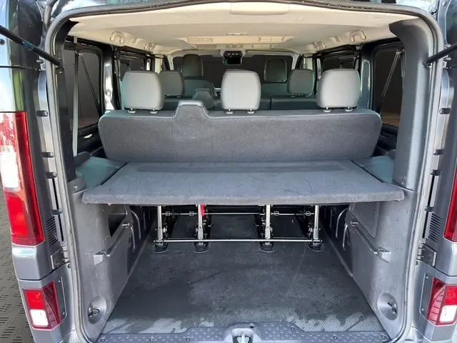 Vue arrière ouverte du Nissan Primastar gris foncé 2025, montrant l'espace de chargement et les sièges passagers.