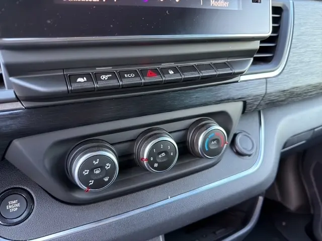 Détail du tableau de bord gris foncé du Nissan Primastar 2025, avec commandes climatisation et bouton démarrage.