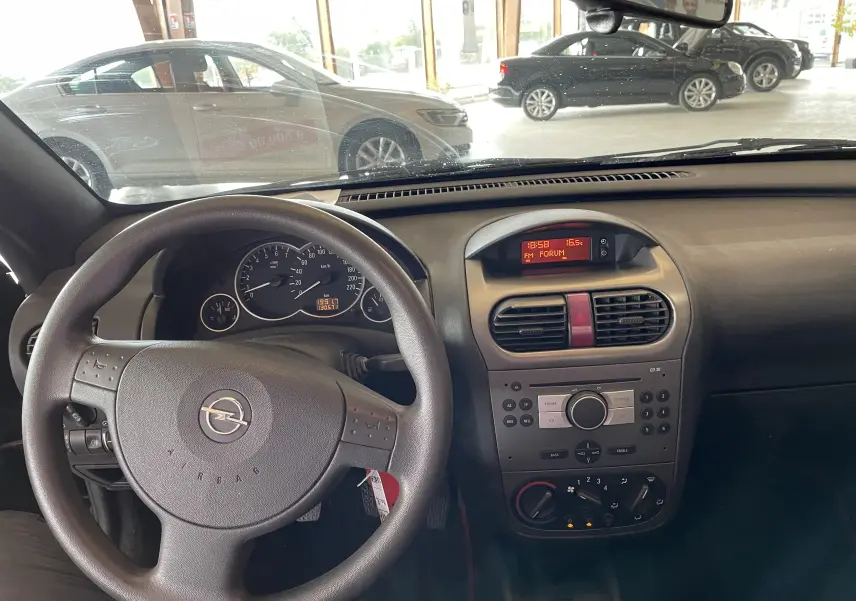 Vue intérieure de l'Opel Tigra Twintop 2006, tableau de bord et volant noir avec commandes intégrées.