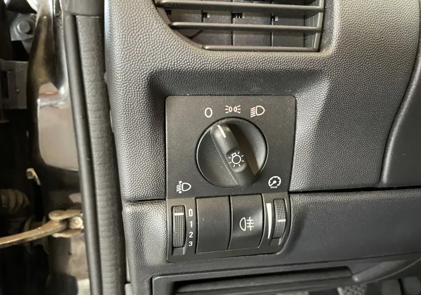 Gros plan sur les commandes d'éclairage intérieures noires du côté gauche d'un Opel Tigra Twintop noir de 2006.