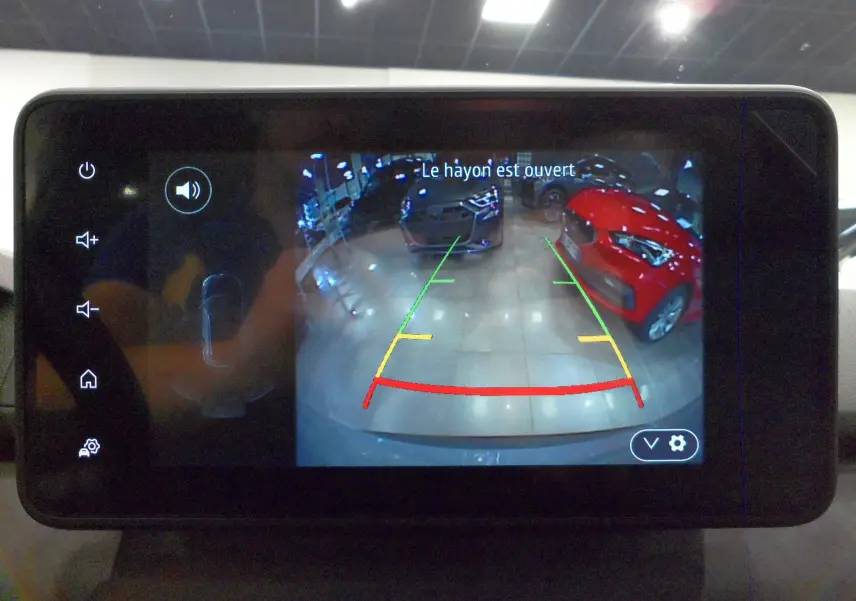 Écran multimédia du Dacia Jogger TCe 110 montrant la caméra de recul avec vue sur deux voitures en intérieur.
