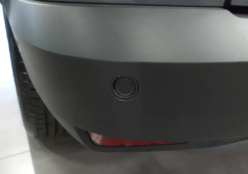 Gros plan sur le capteur de recul noir intégré au pare-chocs arrière gris urbain du Dacia Jogger TCe 110 CH EXTREME 7PL.