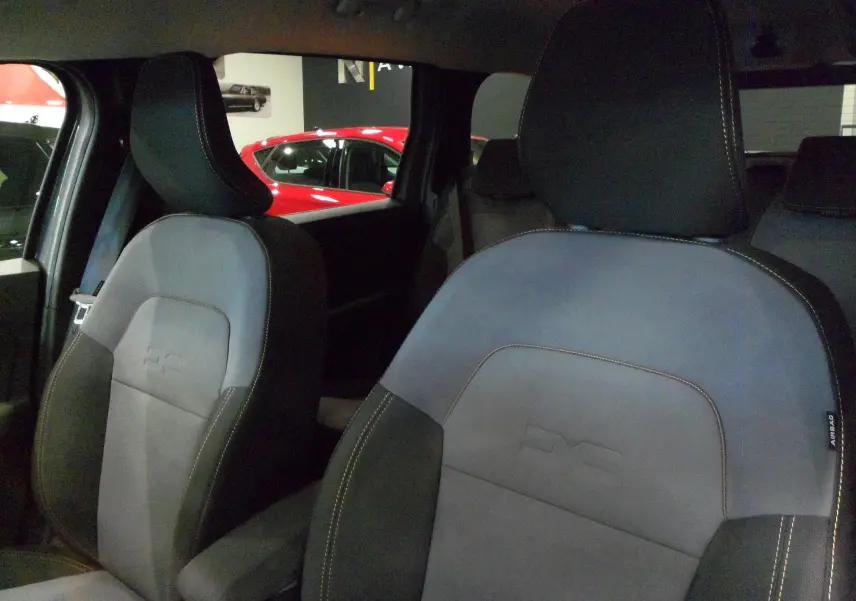 Gros plan sur les sièges avant en tissu gris et noir du Dacia Jogger TCe 110 CH EXTREME 7PL 2025, ambiance intérieure sombre.