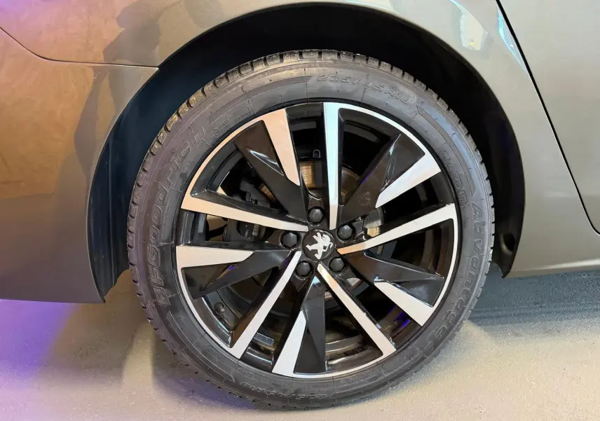 Gros plan sur la jante alu bicolore noire et argentée du côté arrière droit d'une Peugeot 508 gris métallisé.