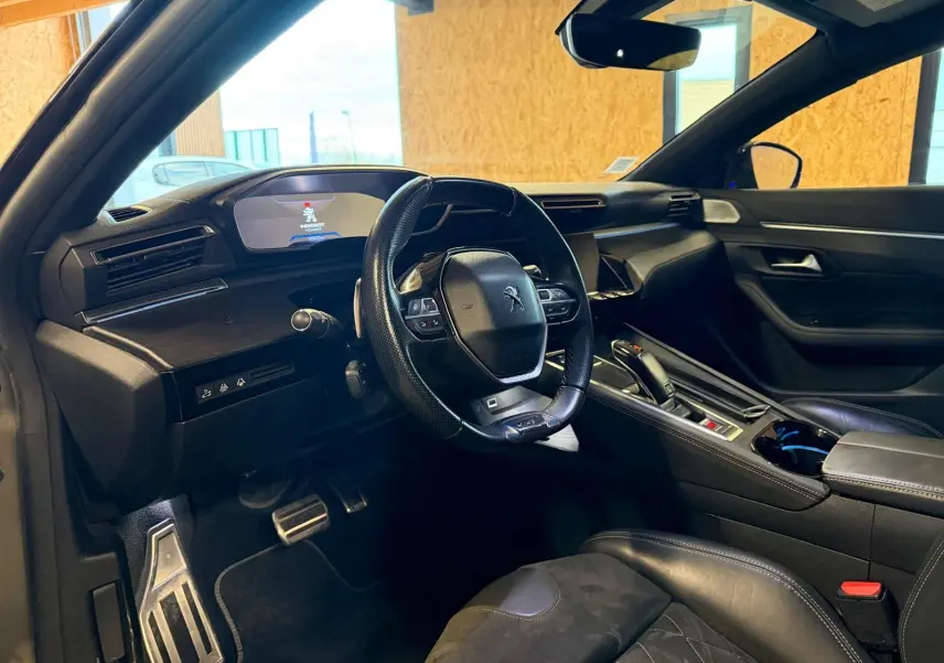 Intérieur Peugeot 508 gris, vue côté conducteur, volant cuir, tableau de bord avec écran numérique et inserts bois.