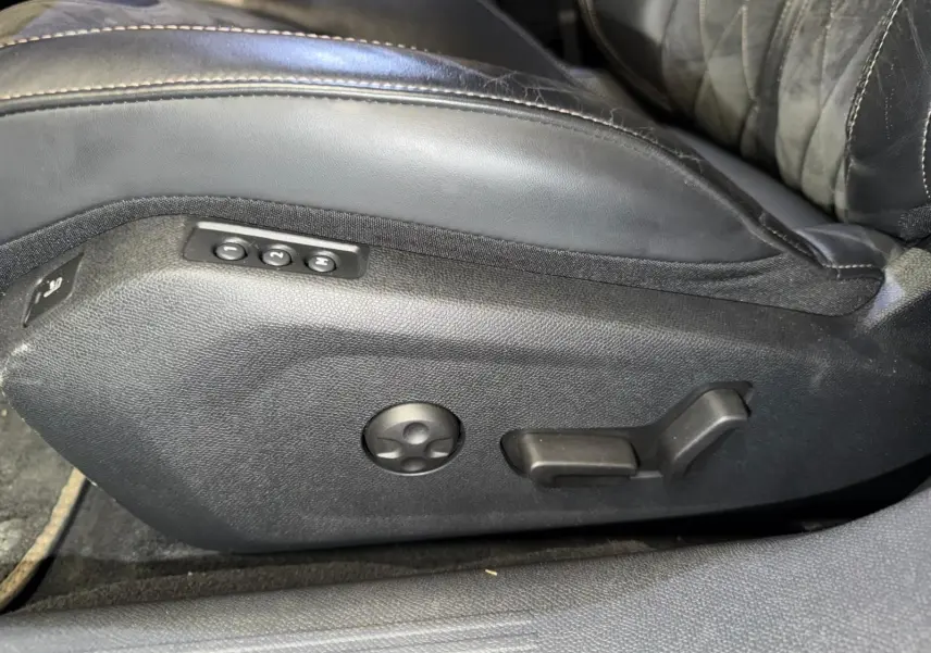 Détail des commandes de réglage électrique du siège avant en cuir noir de la Peugeot 508 gris, vue latérale.