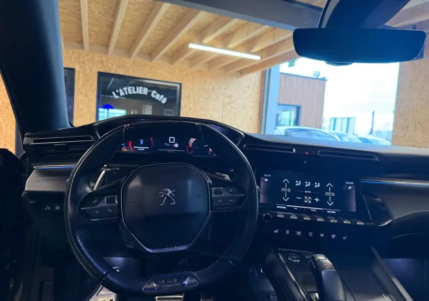 Vue intérieure centrée sur le volant cuir et tableau de bord numérique de la Peugeot 508 gris, avec écran tactile et commandes.
