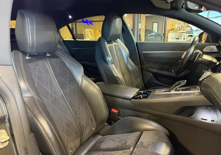 Vue intérieure côté gauche de la Peugeot 508 gris, mettant en valeur les sièges cuir noir et Alcantara avec surpiqûres blanches.