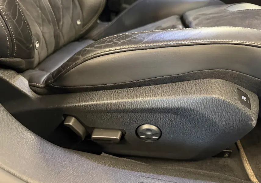 Détail du côté gauche du siège conducteur en cuir noir avec commandes électriques sur Peugeot 508 gris 2019.
