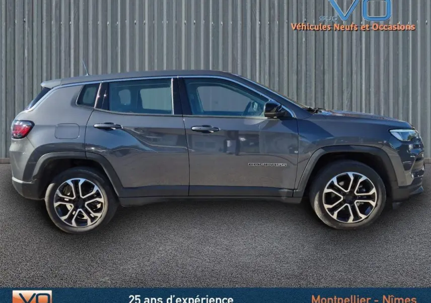 Vue de profil côté gauche d'un Jeep Compass gris 2024 avec jantes alliage 18 pouces sur fond urbain.