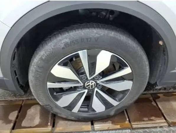 Gros plan sur la roue avant droite d'un Volkswagen T-Roc gris clair, avec jante alliage au design moderne bicolore.