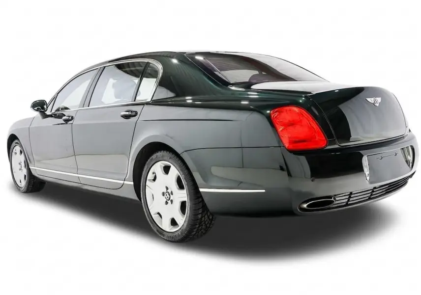 Vue 3/4 arrière droite d'une Bentley Continental Flying Spur vert foncé avec feux arrière rouges et jantes blanches.