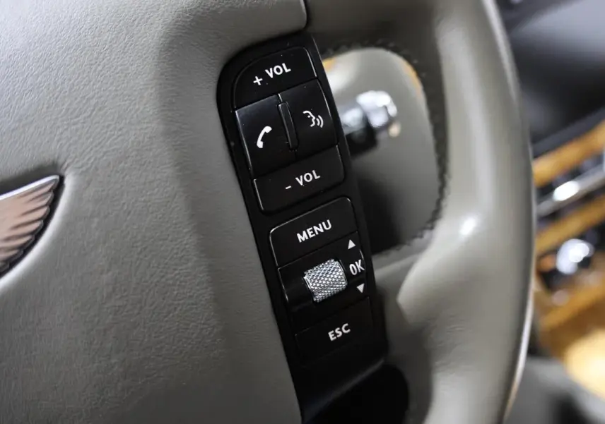 Gros plan sur les commandes noires du volant en cuir gris clair d'une Bentley Continental Flying Spur 2006.