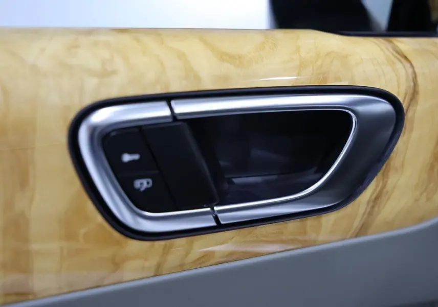 Poignée de porte intérieure en métal brossé sur garniture bois clair d’une Bentley Continental Flying Spur 2006.