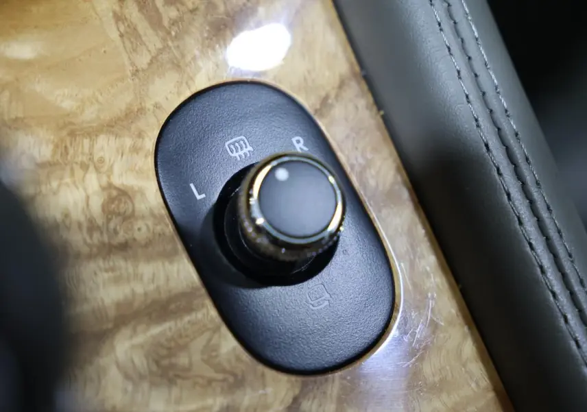 Gros plan sur le bouton de réglage des rétroviseurs sur une console en bois clair d’une Bentley Continental Flying Spur 2006.