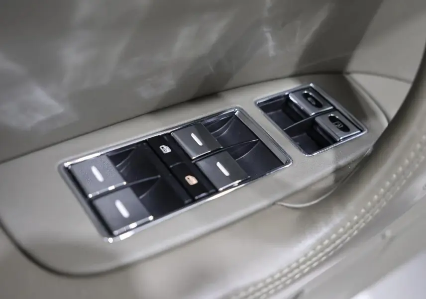 Gros plan sur les commandes de lève-vitres chromées intégrées dans la porte beige du Bentley Continental Flying Spur.