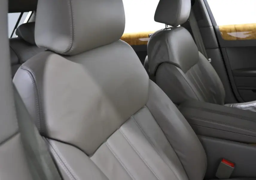 Gros plan sur les sièges avant en cuir gris clair de la Bentley Continental Flying Spur, avec inserts bois en arrière-plan.