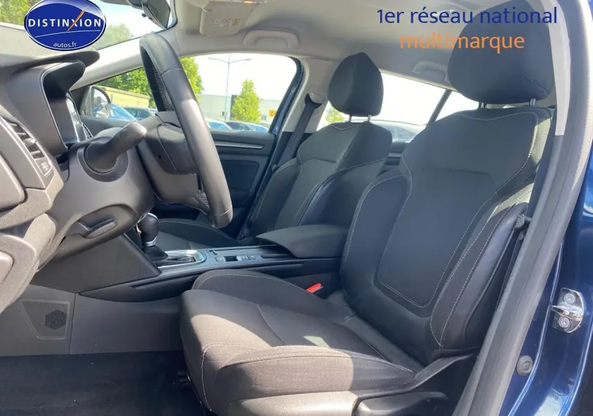 Vue intérieure côté gauche de la Renault Mégane IV Estate bleu, montrant les sièges avant en tissu gris foncé et la console centrale.