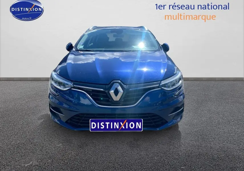 Vue avant d'une Renault Mégane IV Estate bleu électrique, avec calandre chromée et phares LED allumés.